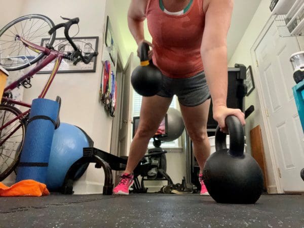 Woman performing a renegade row with kettlebells