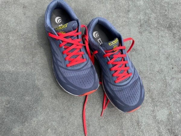 gray running shoes with orange laces on a stone base