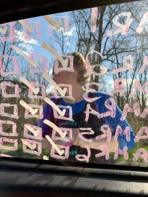 woman seen through a van window that is full of writing