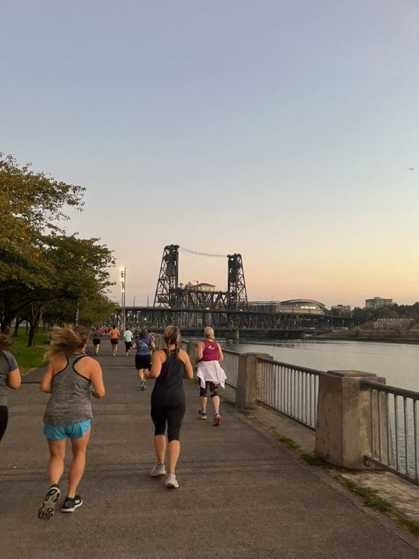 Mother runners running toward the Steel Bridge at sunrise