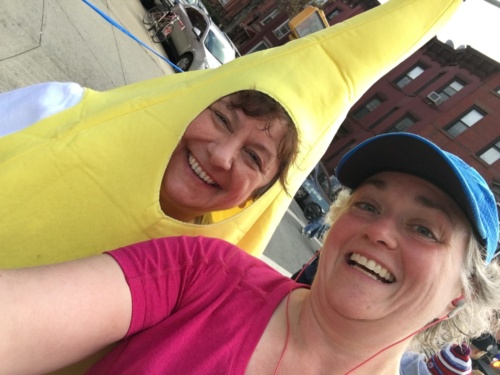 A woman in a blue running hat poses with a woman in a banana suit.