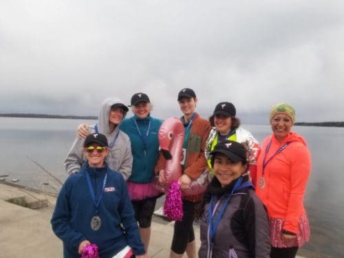 Seven runners in front of the lake. There is an inflatable flamingo.