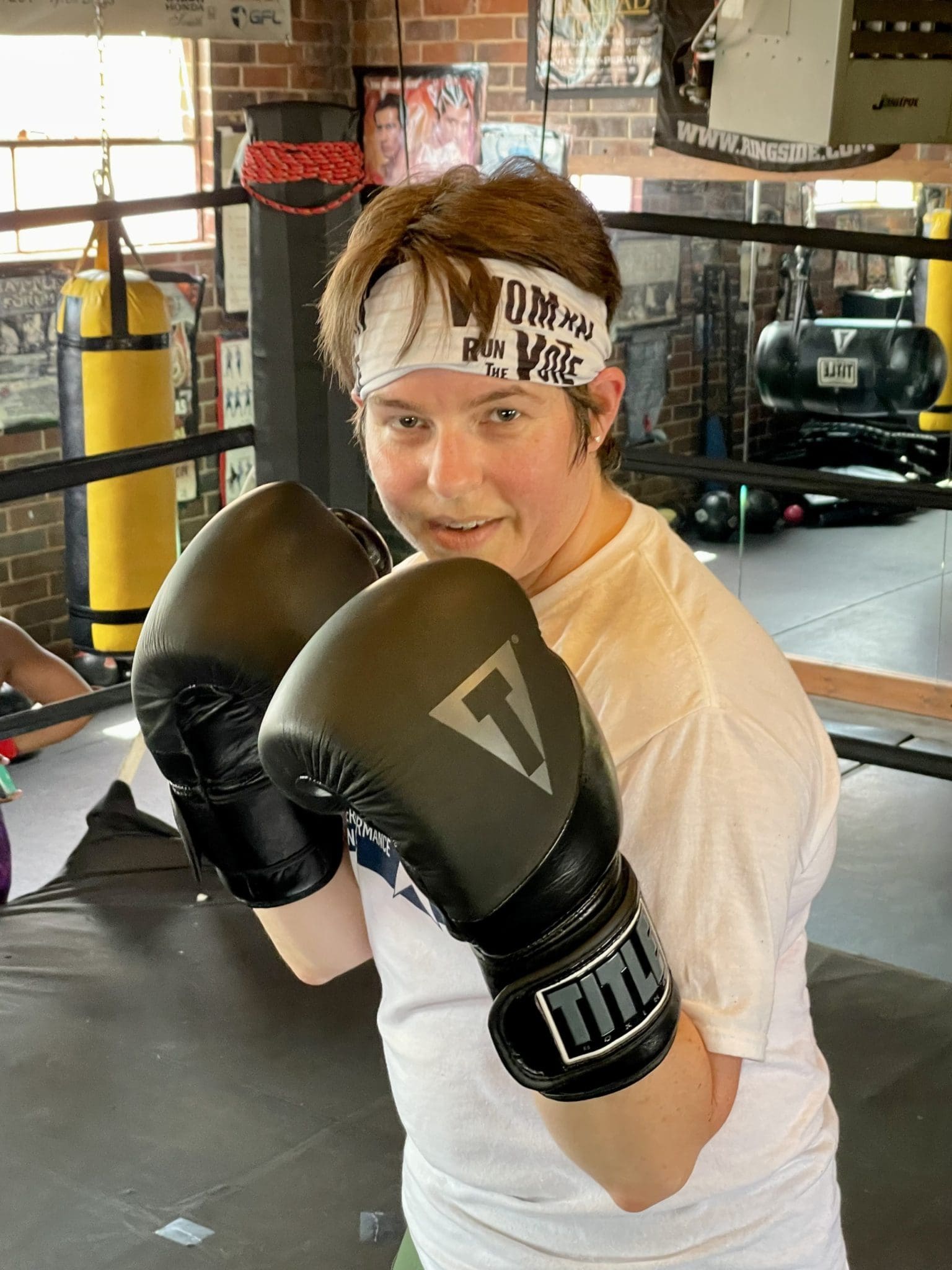 woman wearing boxing gloves, standing in a boxing ring