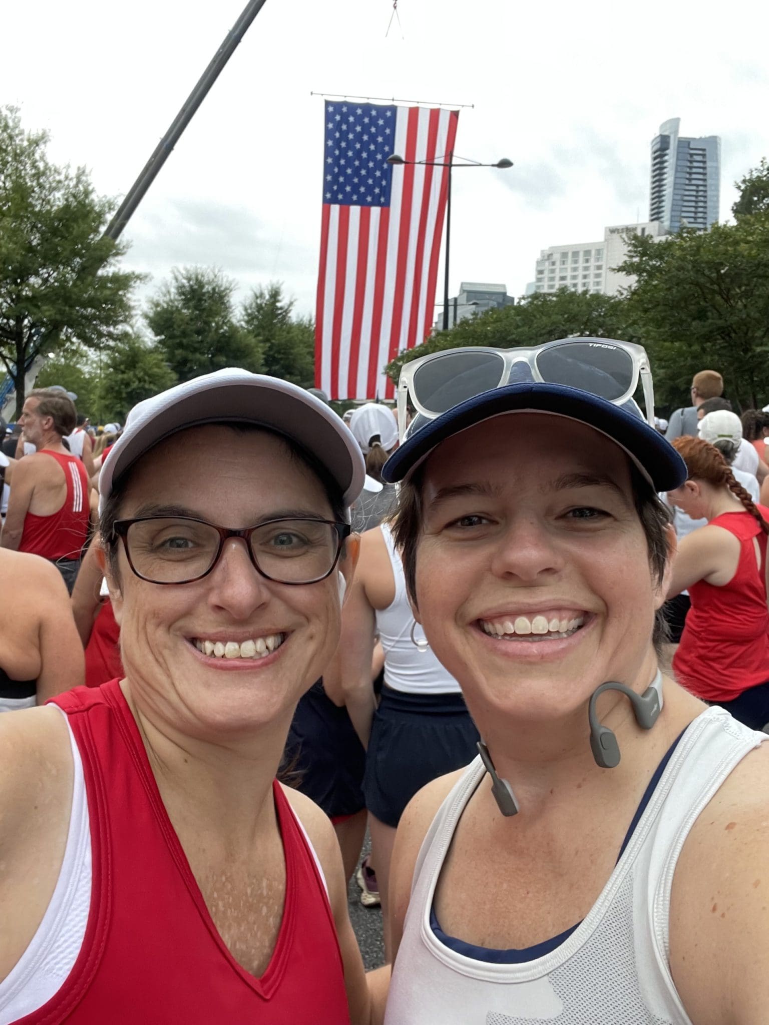 Two smiling women runners taking a selfie in front of a huge American flag
